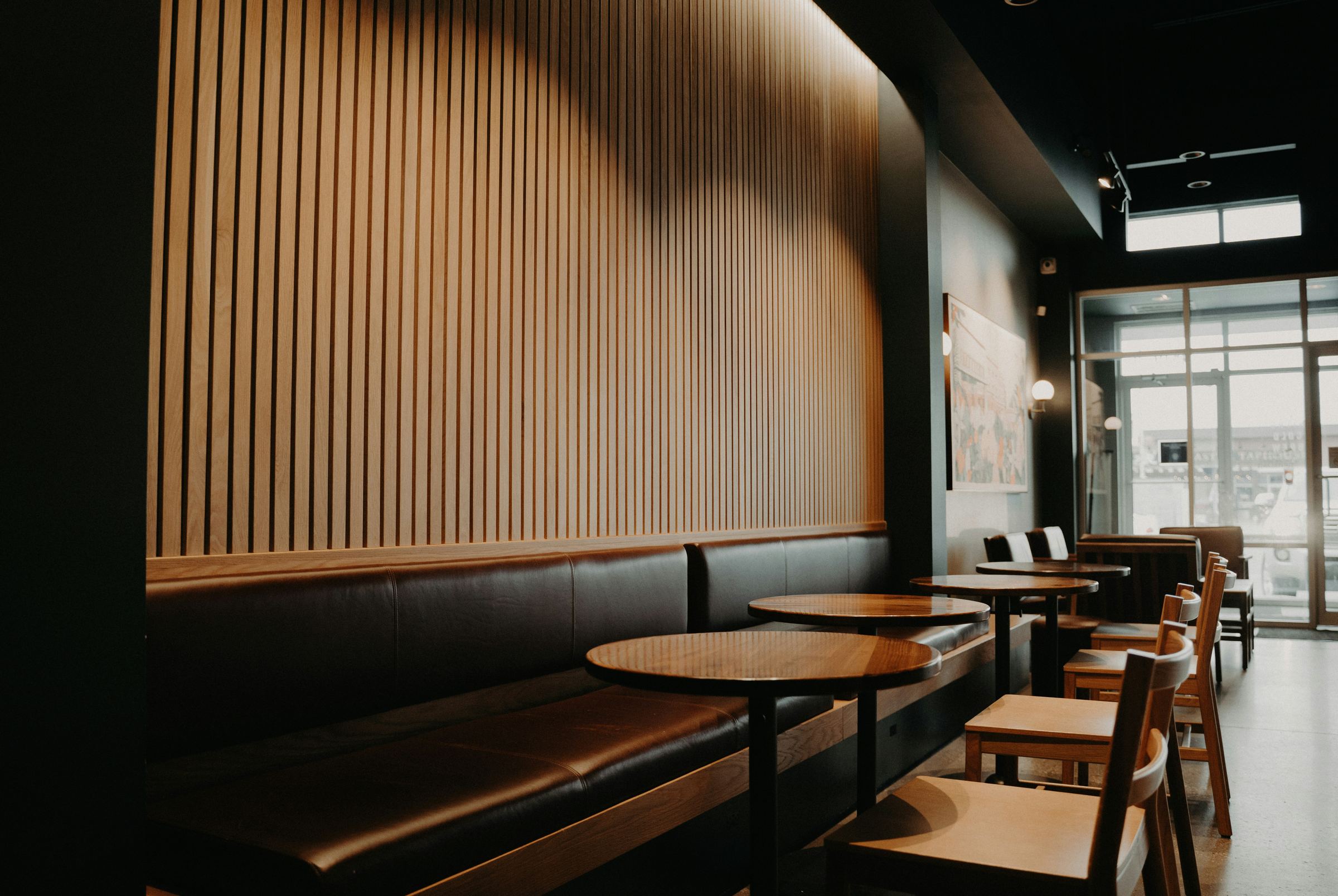 Dark, moody restaurant bar with leather banquette and round tables